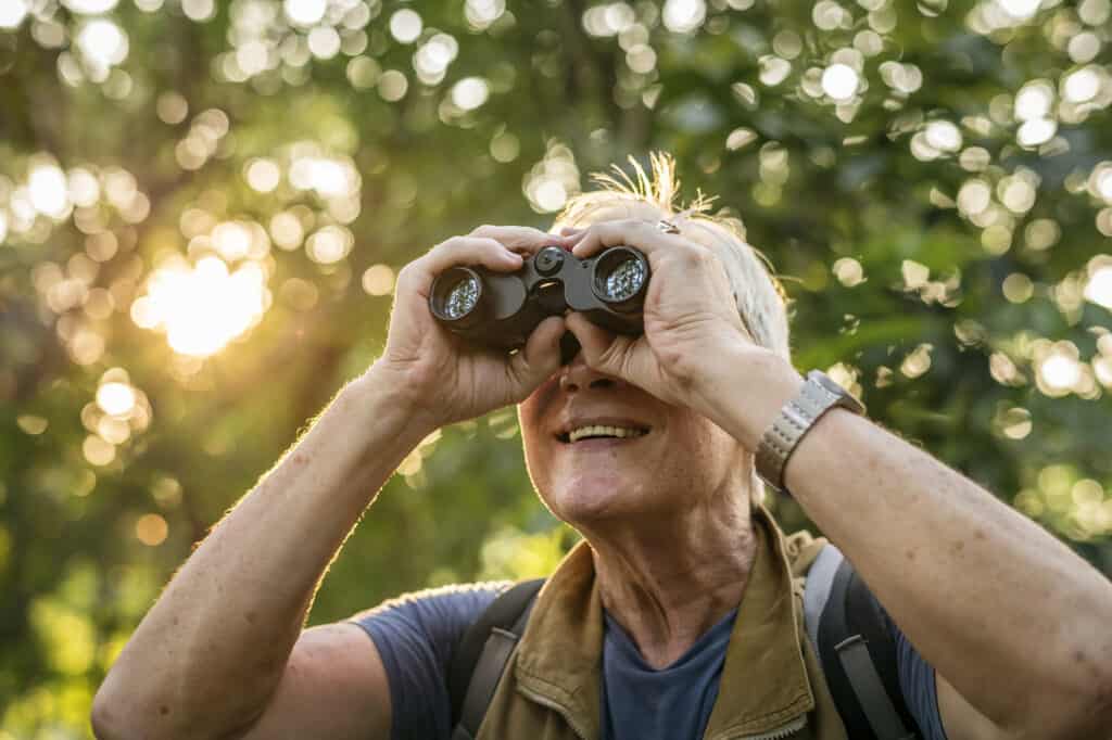 Senior man watching birds with binoculars